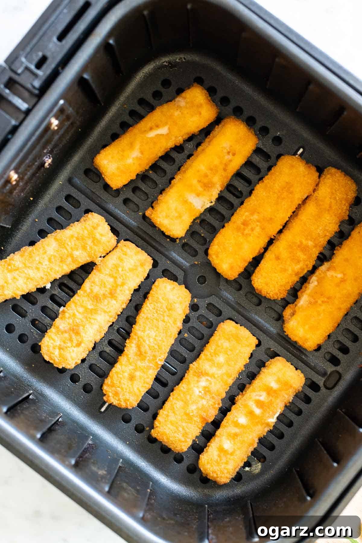 Crispy Air Fryer Fish Sticks 4 Freshly cooked, golden-brown fish sticks resting in an Air Fryer basket.
