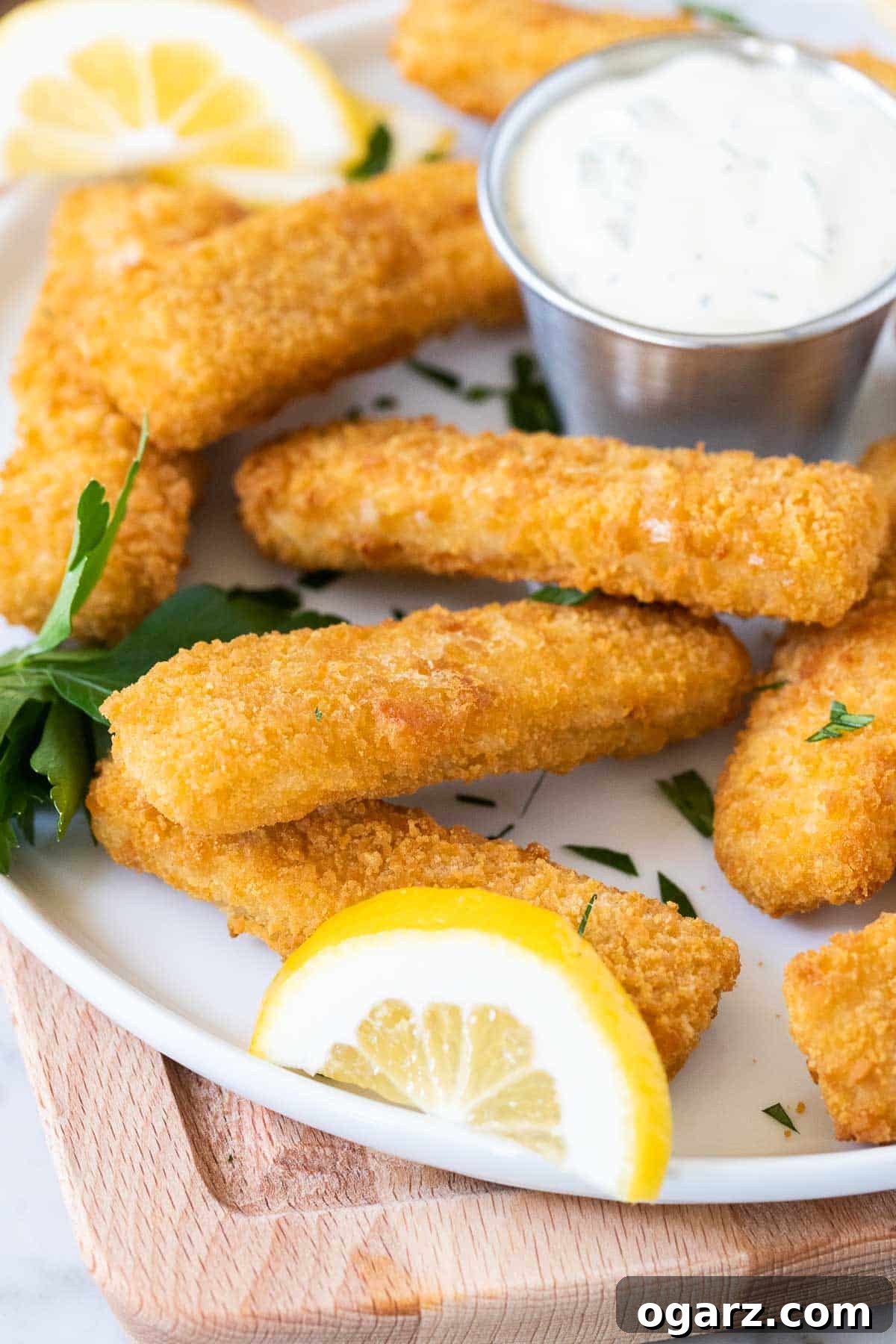 Crispy Air Fryer Fish Sticks 5 A vibrant plate featuring crispy fish sticks, a fresh lemon slice, and a dollop of creamy tartar sauce.