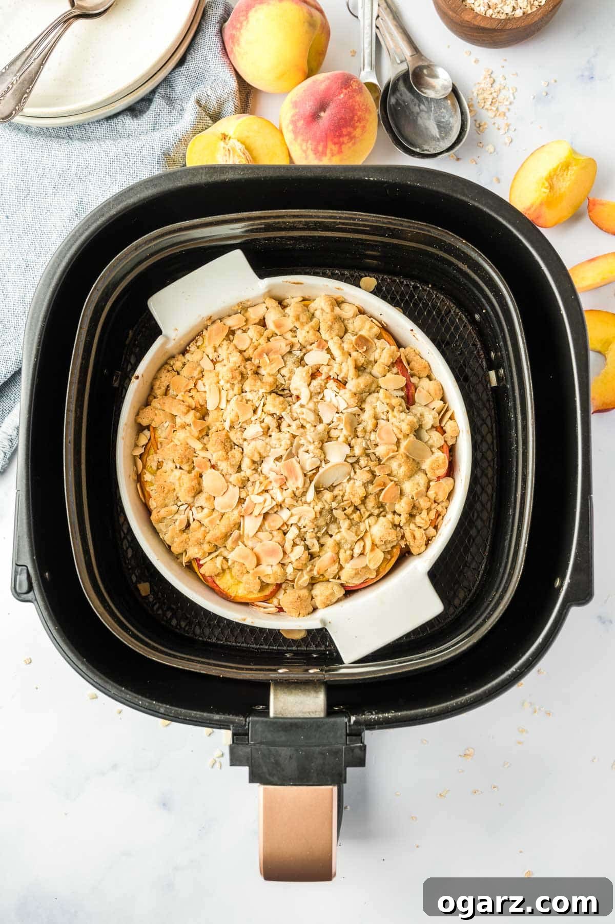 What's the Best Air Fryer for You 3 A delicious peach crumble, perfectly cooked and golden brown in a baking pan, resting inside an air fryer basket