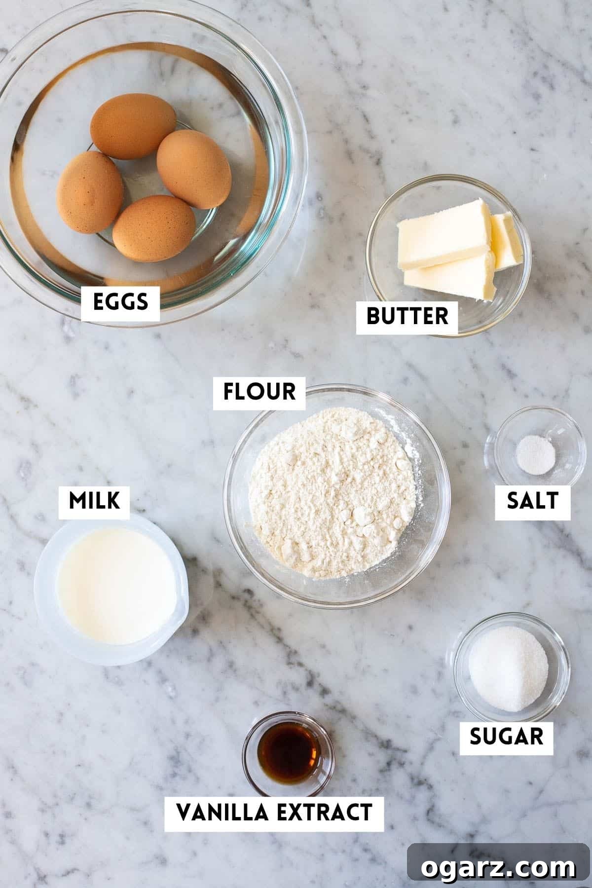 Spectacular Oven-Baked Pancake 3 Various ingredients for making a classic German Pancake, including flour, eggs, milk, vanilla, sugar, and butter.