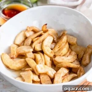 Baked apples tossed in cinnamon and maple syrup in a serving dish.