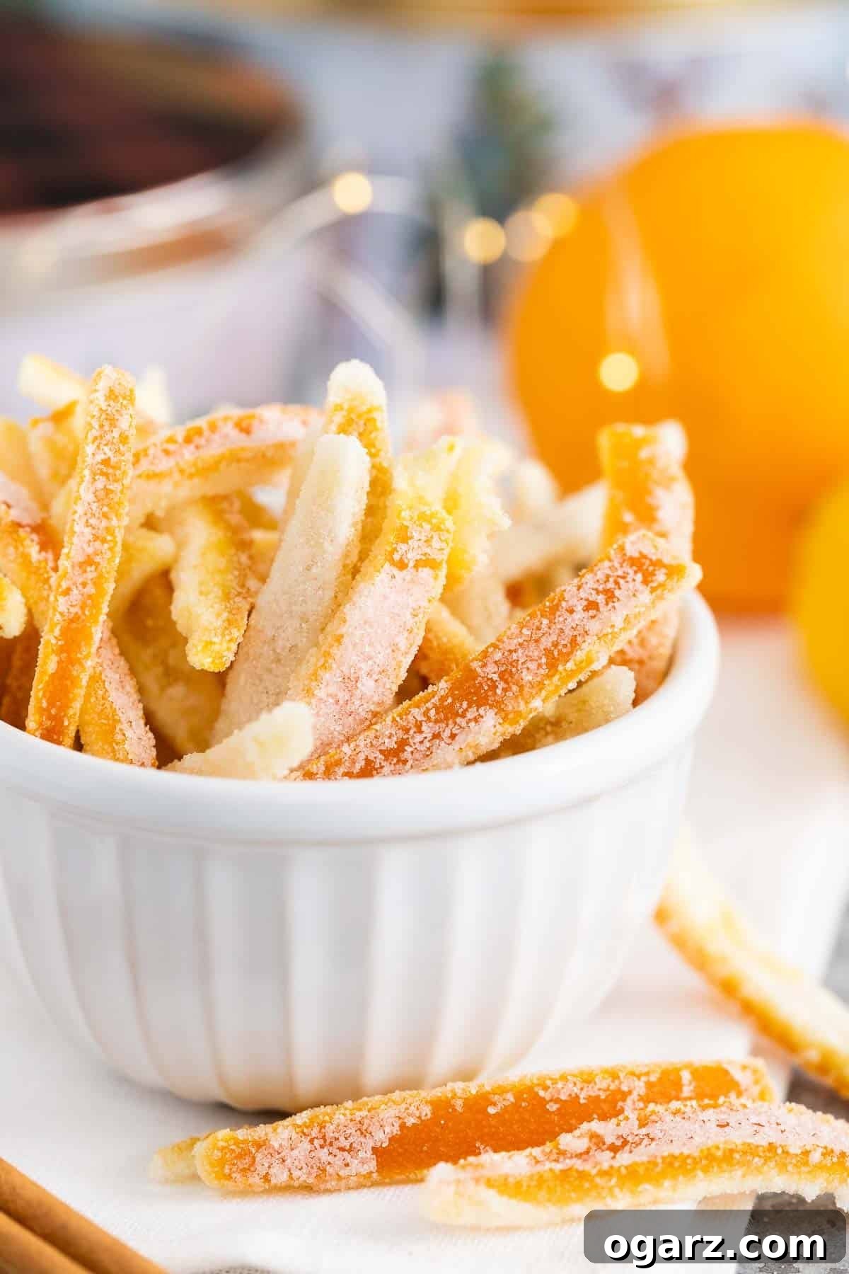 Golden Orange Gems 7 Candied peel in a small white bowl with oranges in the background.