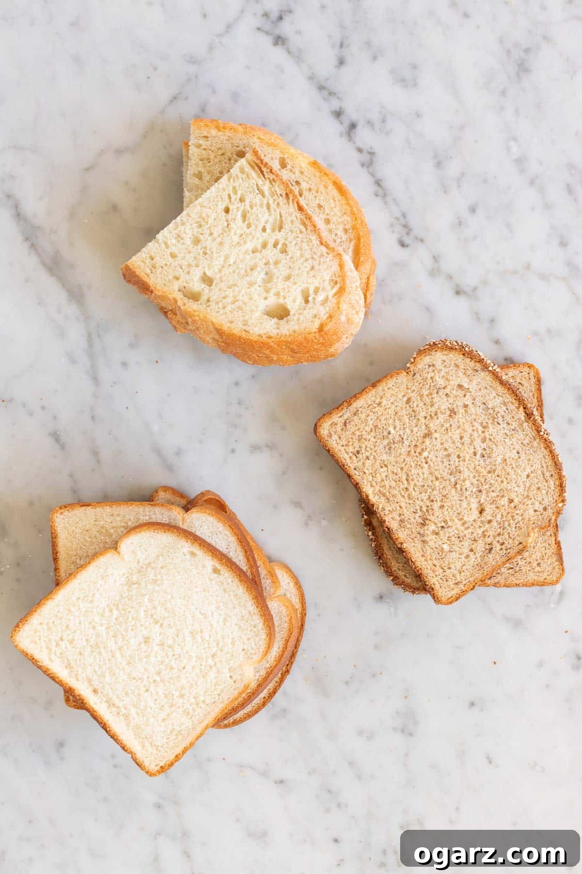 Crispy Air Fryer Toast 3 Different kinds of bread slices stacked on a marble board, ready for toasting.