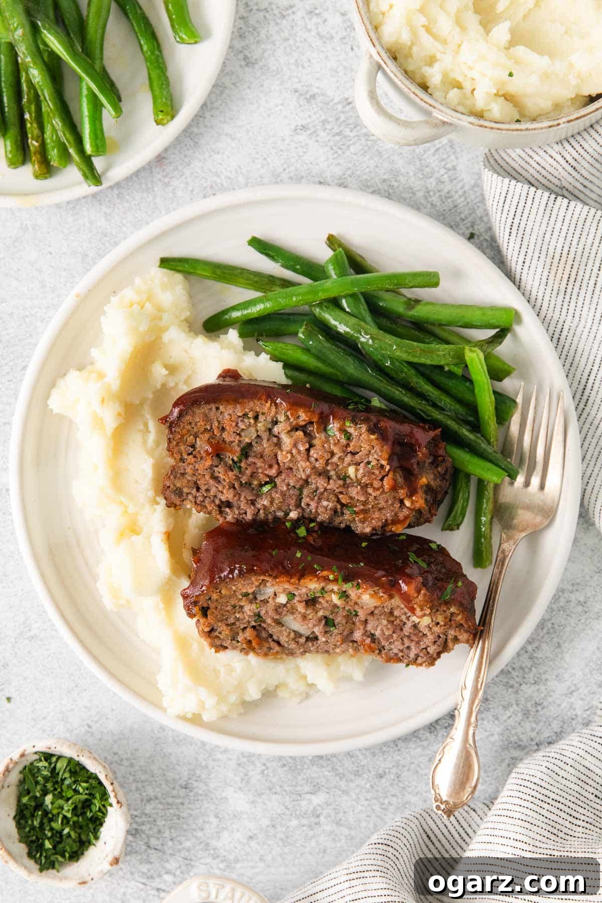 A plate with two slices of air fryer meatloaf, creamy mashed potatoes, and vibrant green beans, ready to be enjoyed.