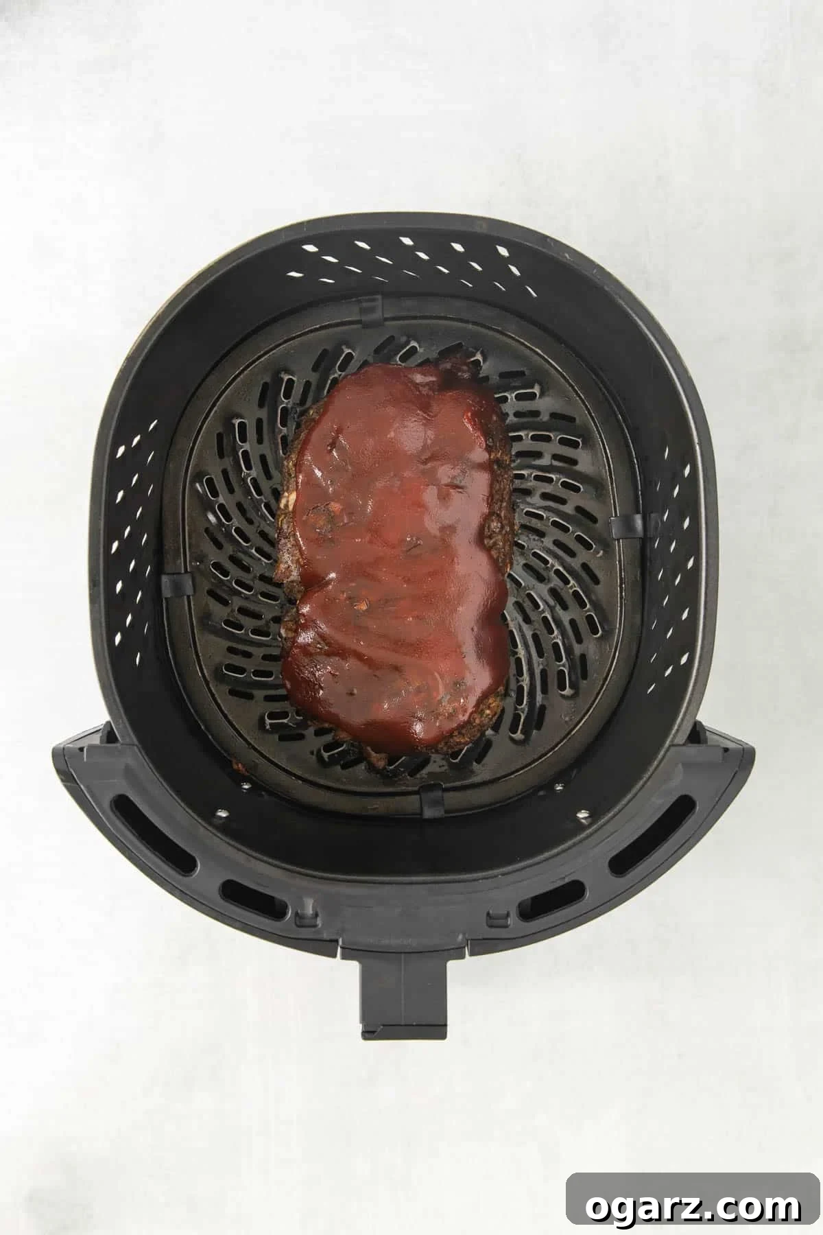 A perfectly glazed meatloaf resting in an Air Fryer basket, showcasing its crispy exterior and rich topping.