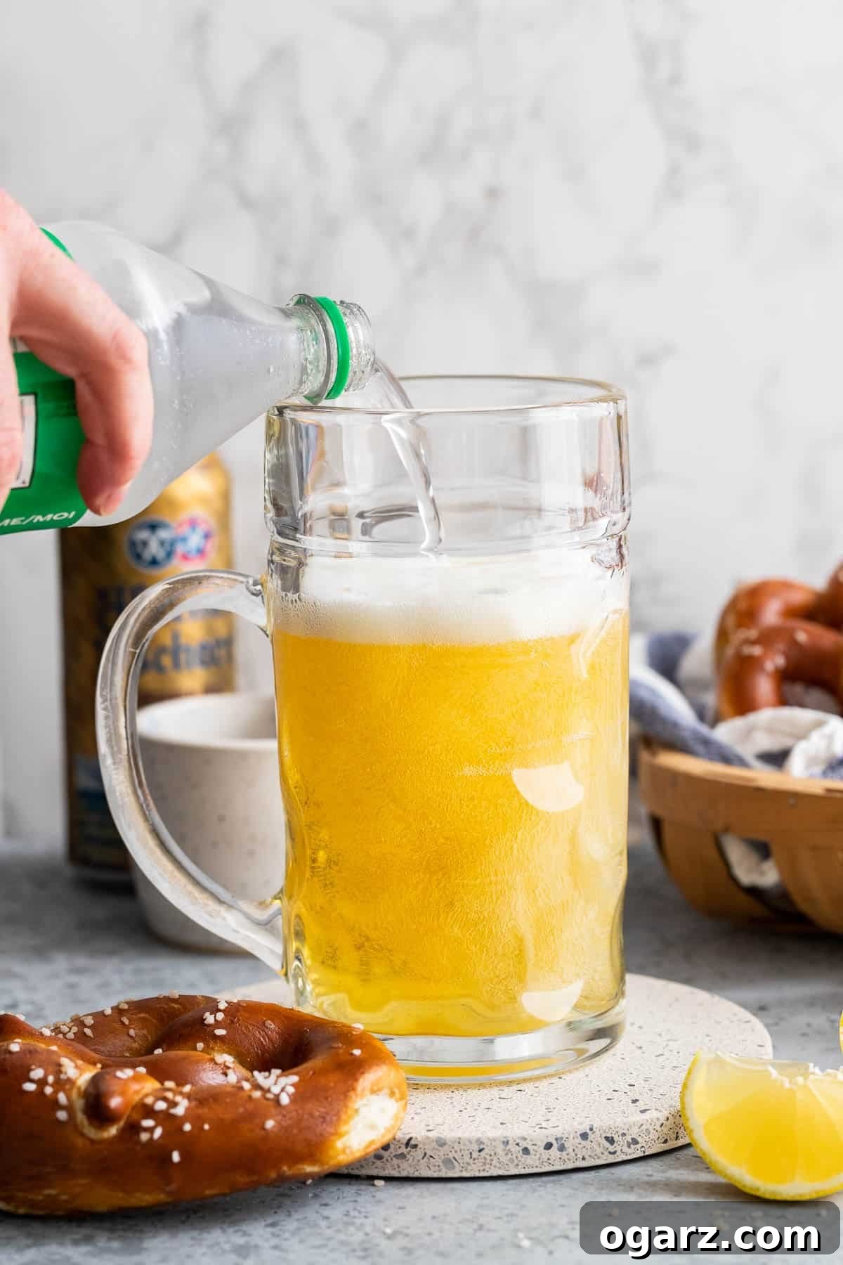 Zesty Lager Blend 5 Sparkling lemonade being carefully poured into a beer stein already containing beer, completing the Radler mixture.