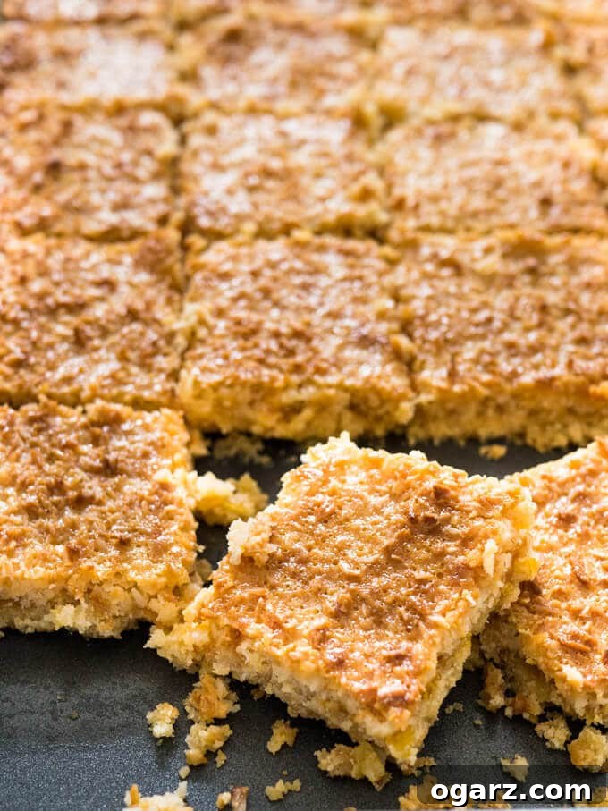 Close-up of Tropical Coconut Squares, highlighting the distinct layers of shortbread, jam, and coconut with caramelized condensed milk.