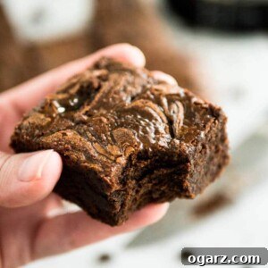 A hand holding up a cold brew coffee brownie with a bite taken out.