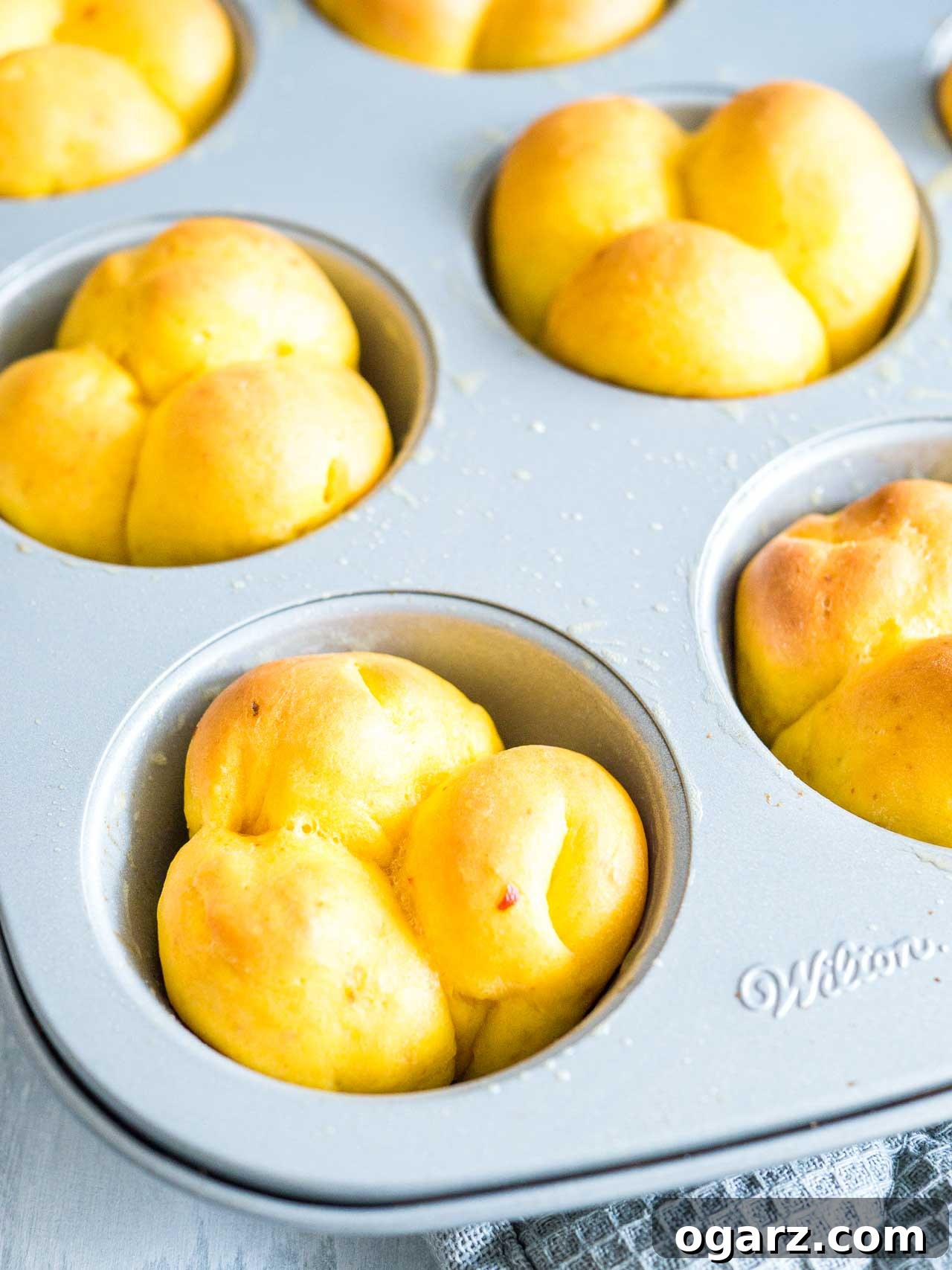 Pillowy Pumpkin Dinner Rolls 5 A muffin pan full of perfectly baked golden pumpkin dinner rolls, still warm from the oven.