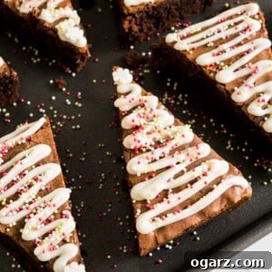 Festive Gingerbread Brownies 6 A black baking sheet with gingerbread Christmas brownies with a triangular shape and waves of frosting and sprinkles to make it look like small Christmas trees.