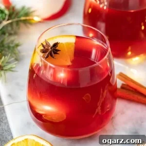 Two glass mugs filled with Kinderpunsch garnished with orange slices and star anise.