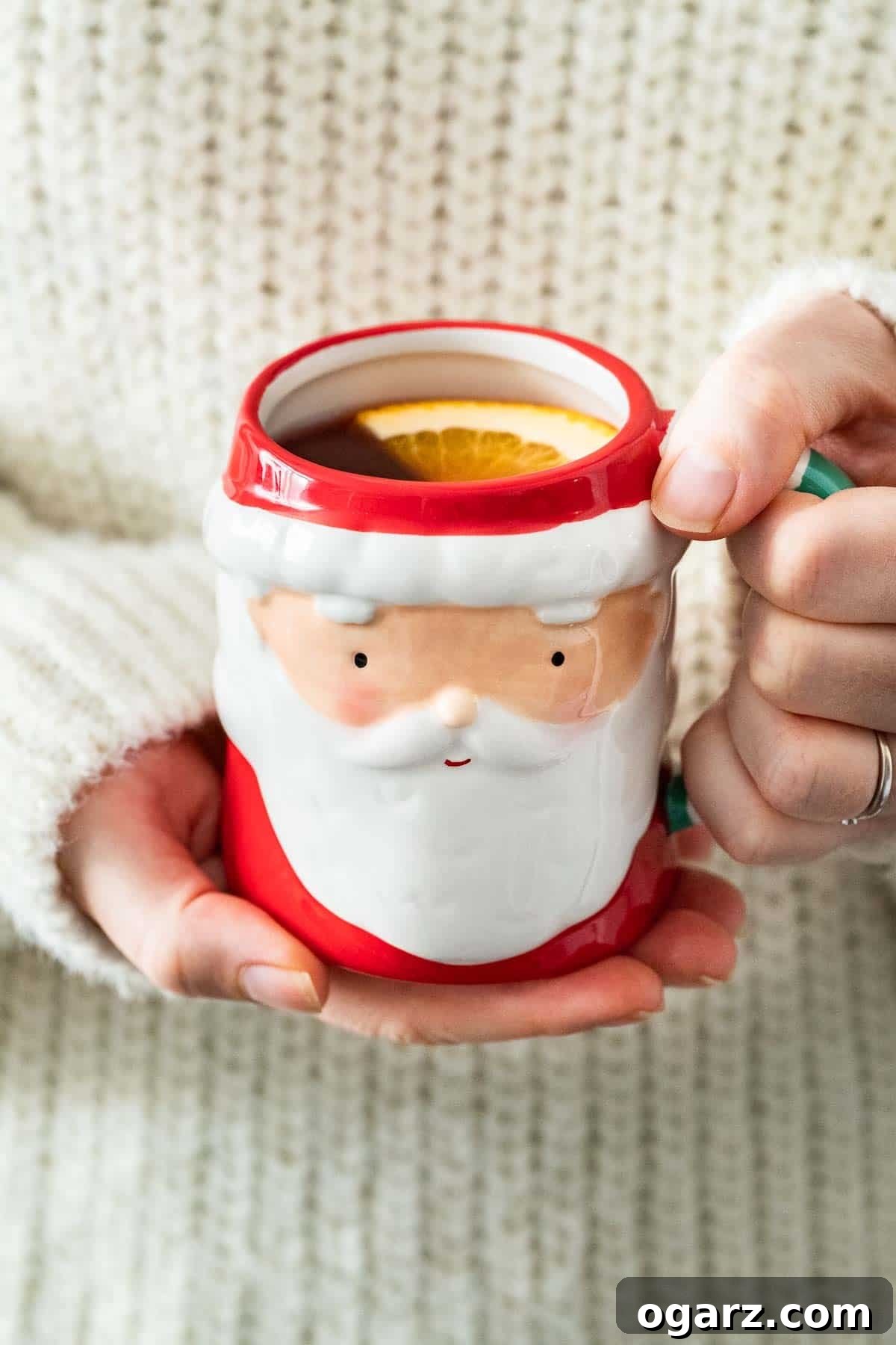 Festive Kids' Punch 5 Two hands holding a Santa-shaped mug filled with Kinderpunsch.