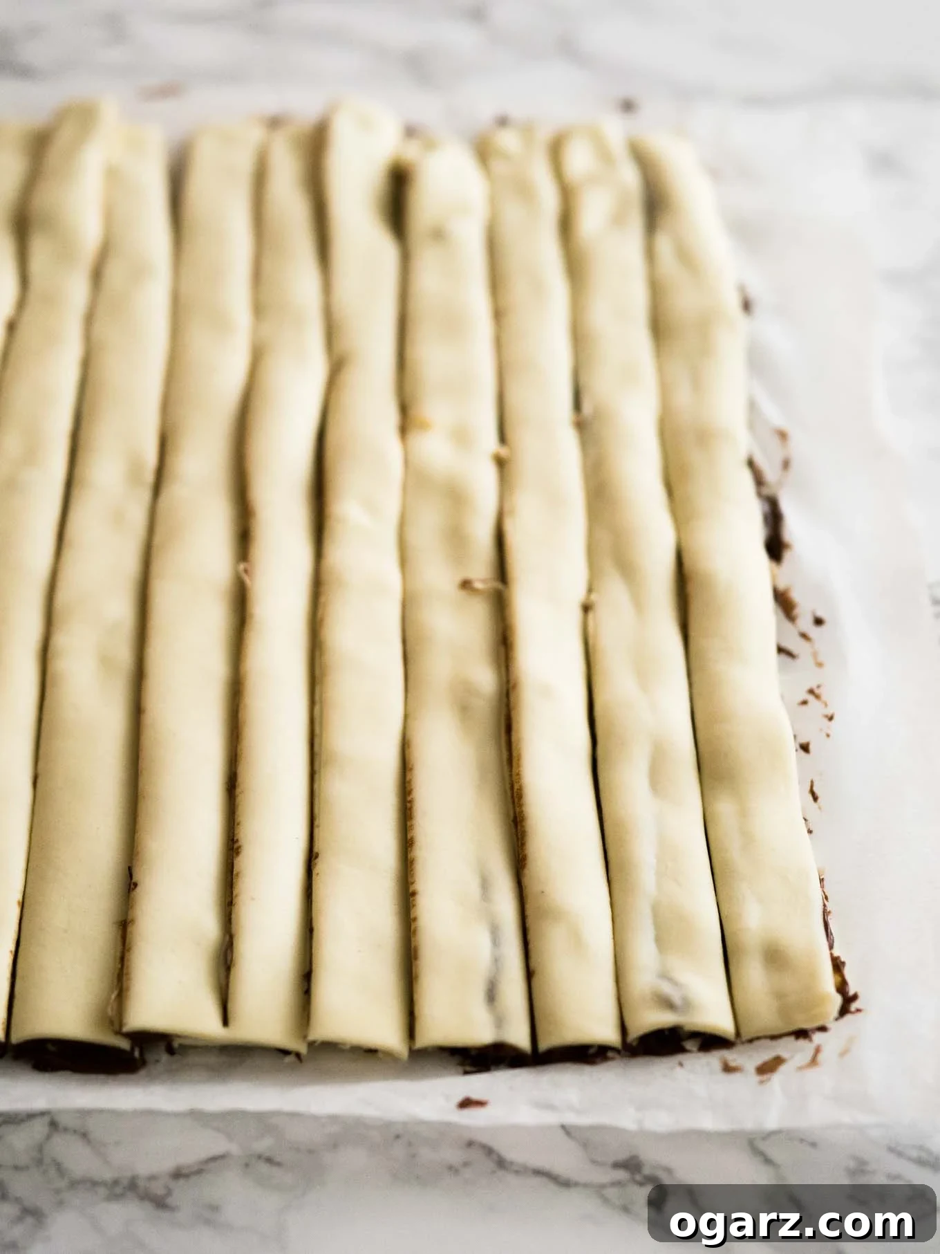 Simple Swirl Nutella Danish 4 Two sheets of puff pastry spread with Nutella, one sprinkled with chopped hazelnuts, ready to be folded.
