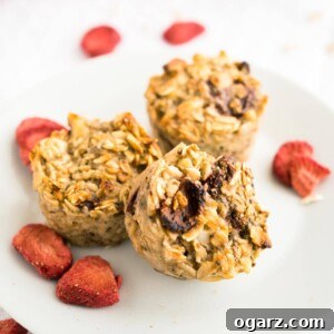 Healthy Strawberry Baked Oatmeal Cups 6 Three strawberry baked oatmeal cups on a white plate garnished with some dried strawberries.