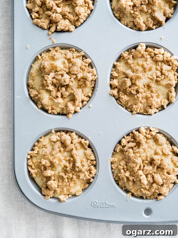 Freshly Baked Banana Crumb Muffins in a Pan A top-down shot showing a muffin pan filled with banana muffins, each generously topped with streusel, ready to be baked or just out of the oven.