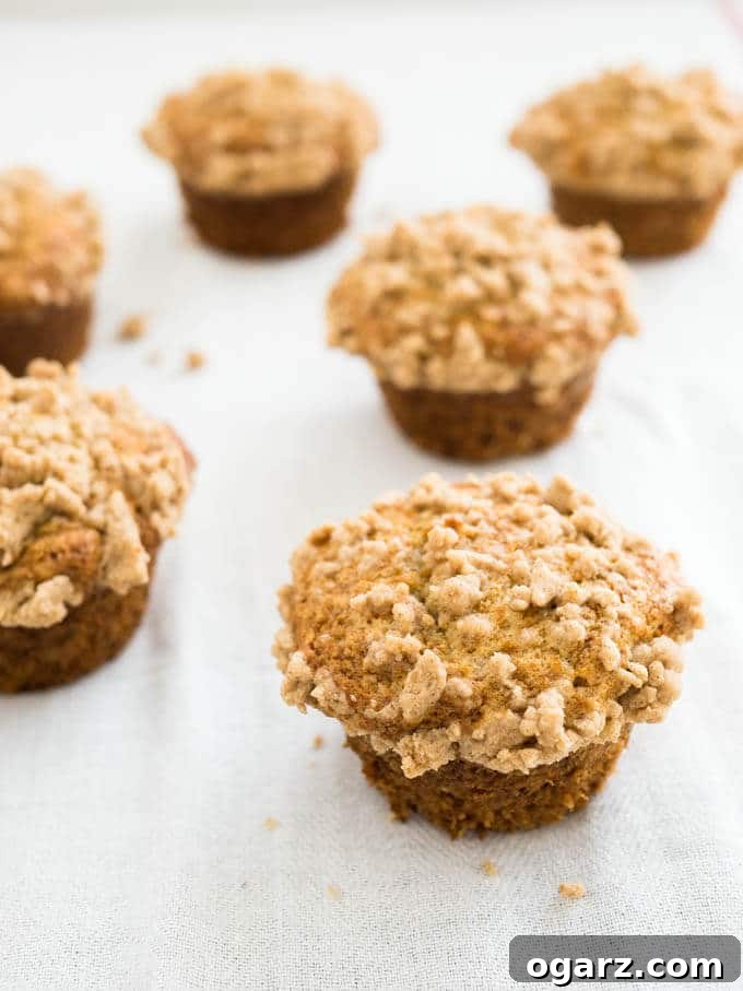 Delicious Banana Crumb Muffins Ready to Enjoy Several banana muffins with streusel topping arranged on a grey marble surface, showcasing their golden-brown tops and moist texture.