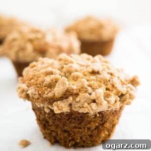 A banana muffin with streusel topping with more muffins in the background.
