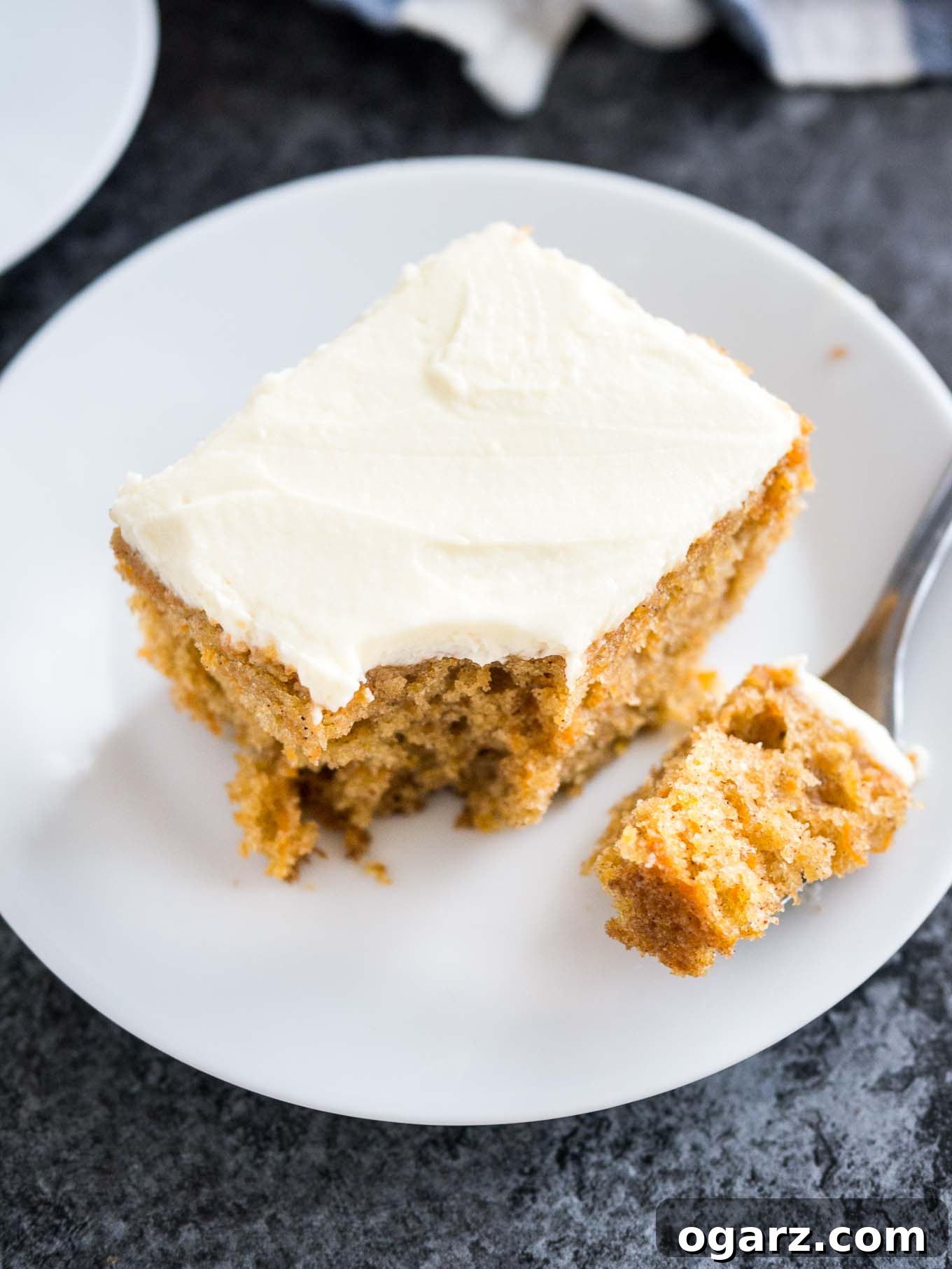Effortless Carrot Cake Guide 4 A beautiful slice of frosted carrot cake, showing the moist layers and the smooth cream cheese frosting, presented on a white plate with a subtle blue pattern.