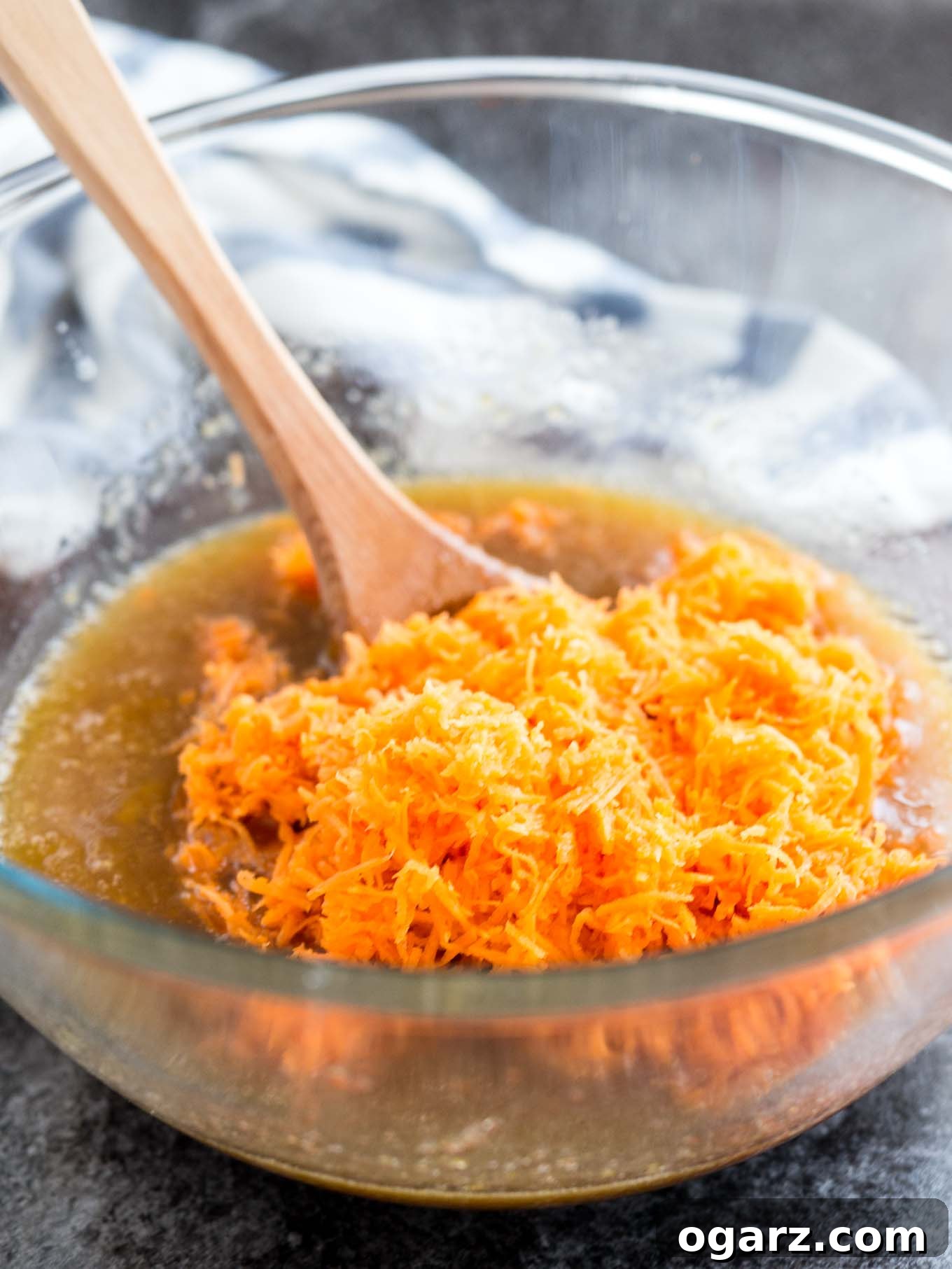 Effortless Carrot Cake Guide 5 A clear glass bowl filled with finely grated fresh carrots, ready to be added to the cake batter.
