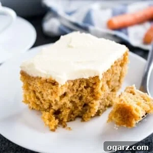 Effortless Carrot Cake Guide 6 A piece of carrot cake with cream cheese frosting on a white plate.
