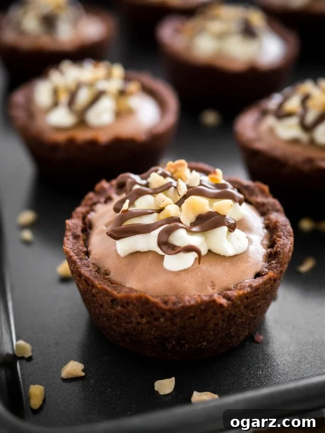 Decadent Nutella Mousse Cookie Cups 2 Close-up of a Nutella Mousse Cookie Cup on a black surface. More cookie cups are in the background.