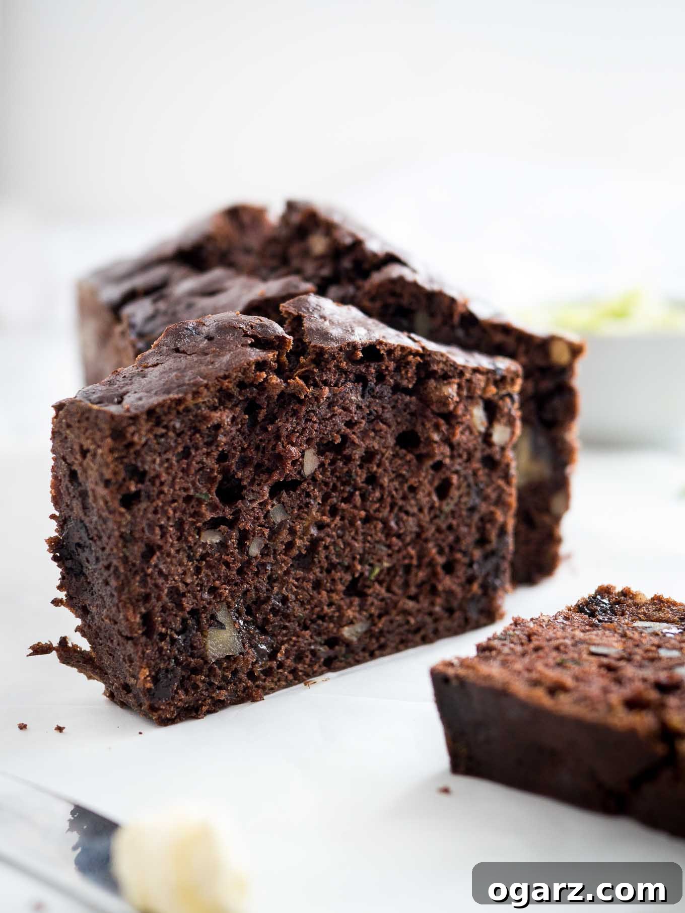 Decadent Chocolate Zucchini Bread 5 A loaf of chocolate zucchini bread with two slices cut off, one standing one lying in front.