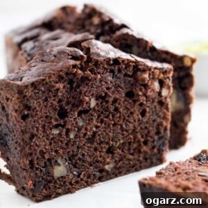 Decadent Chocolate Zucchini Bread 6 Close-up of a loaf of chocolate zucchini bread with two slices cut off, one standing one lying in front.