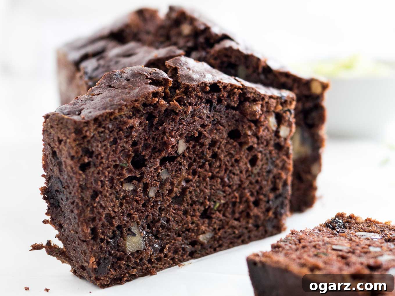 Decadent Chocolate Zucchini Bread 7 Close-up of a loaf of chocolate zucchini bread with two slices cut off, one standing one lying in front.