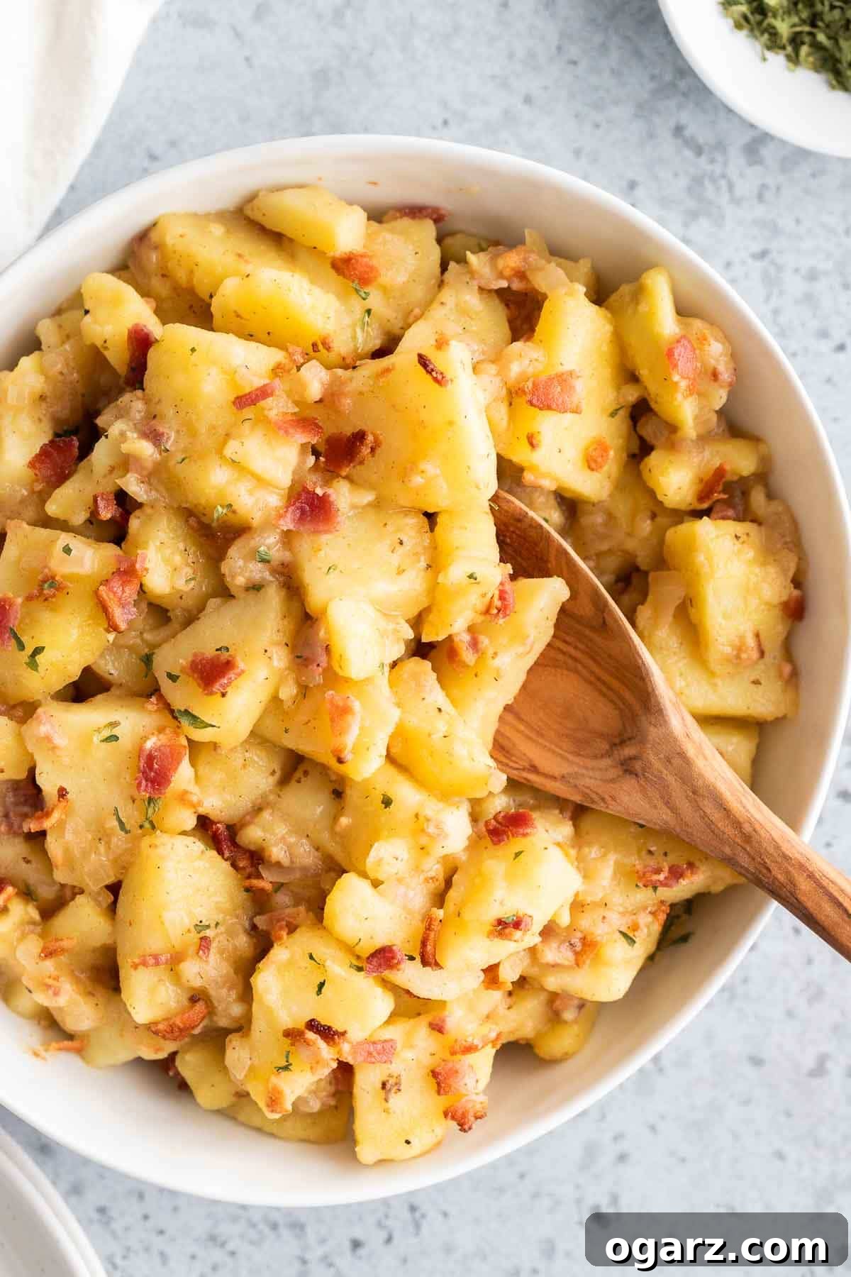 German potato salad in a serving bowl with a spoon sticking out