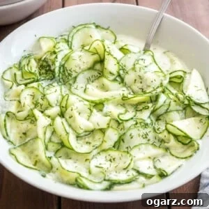 German Cucumber salad in a white salad bowl on a wooden table with a spoon in it