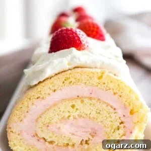 Close-up of a strawberry swiss cake roll topped with whipped cream and strawberries on a rectangular serving platter.
