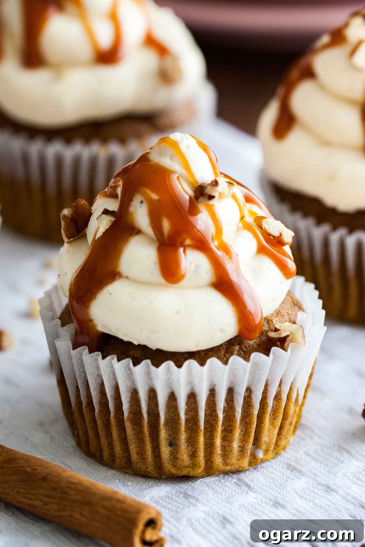 Indulgent pumpkin cupcake adorned with a swirl of brown butter frosting, rich salted caramel, and chopped walnuts, presented on a charming pink plate.
