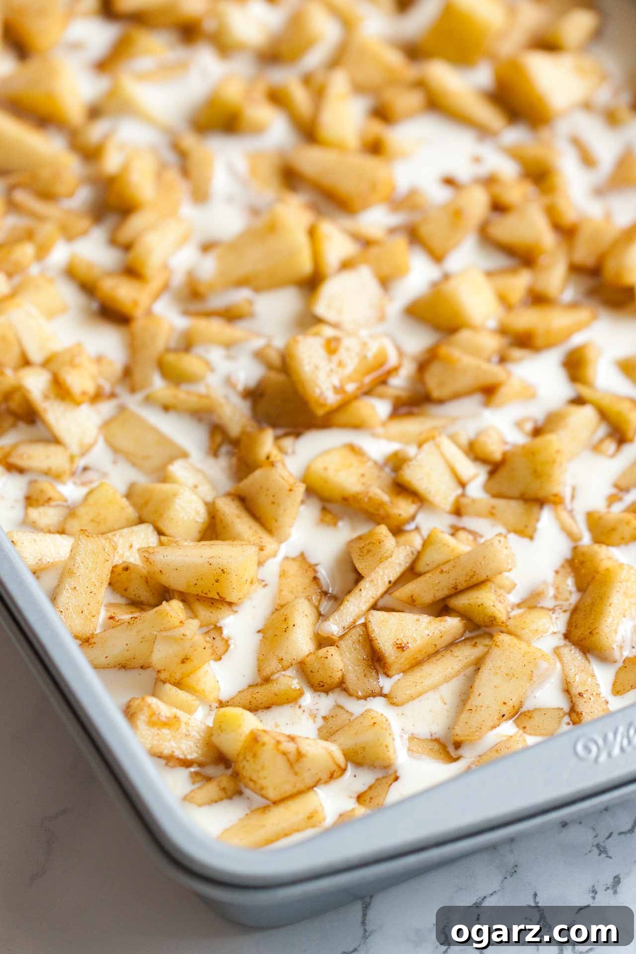 Salted Caramel Apple Cheesecake Bars 5 A baking sheet with a cheesecake layer topped with apple pieces.