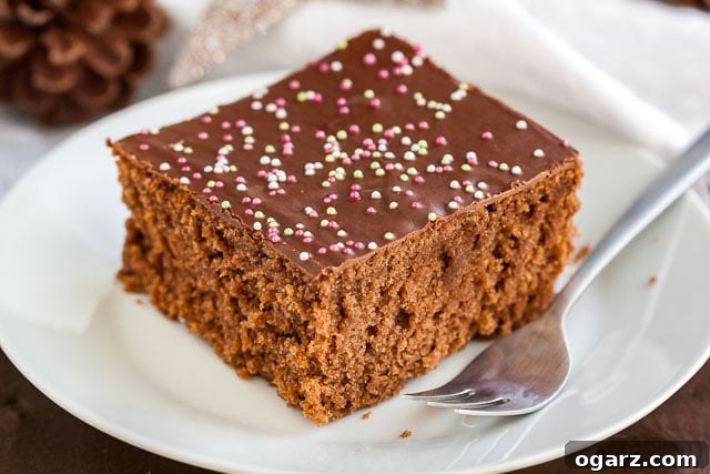 Quick & Cozy Spice Cake 6 A beautifully presented square of chocolate topped spice cake with a fork on a simple white plate, ready for tasting.