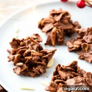 Crunchy Cornflake Delights 5 Chocolate covered clusters of corn flakes and almonds on a grey plate, garnished with almonds and cranberries.