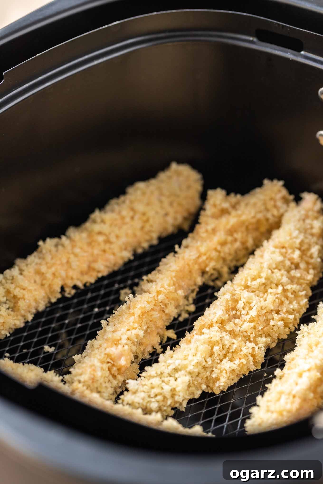 Air Fryer Pickles are super crispy and make a great game day or party snack! Fried Pickles made in the Air Fryer are healthier because they are made with a lot less oil and have a crunchy panko breadcrumbs coating that makes them taste even better than the deep fried original. #AirFryerRecipes #FriedPickles Breaded pickle spears in an air fryer basket.