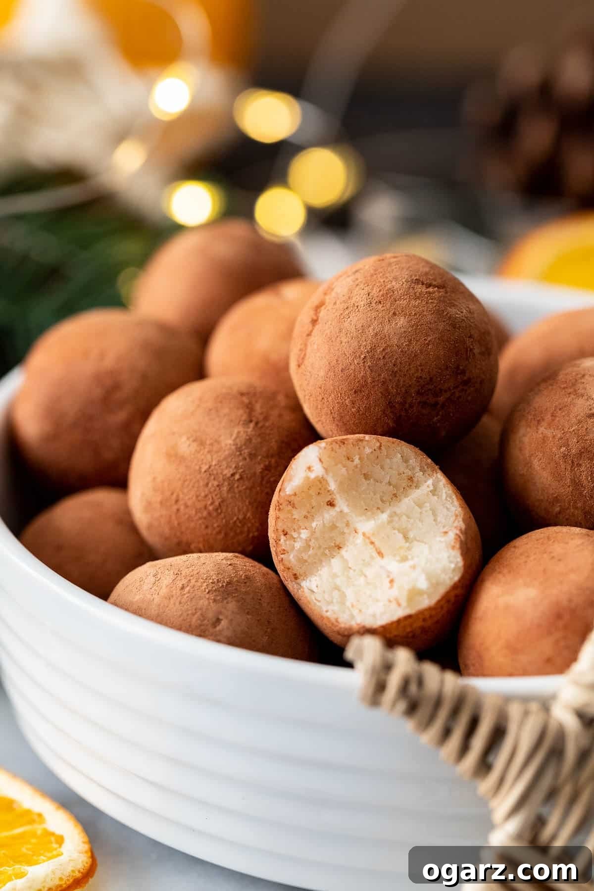 Crafting Delicious Marzipan 4 A white bowl filled with traditional German marzipan potatoes, each rolled in cocoa powder, with one ball having a bite taken out of it to reveal the creamy marzipan interior.