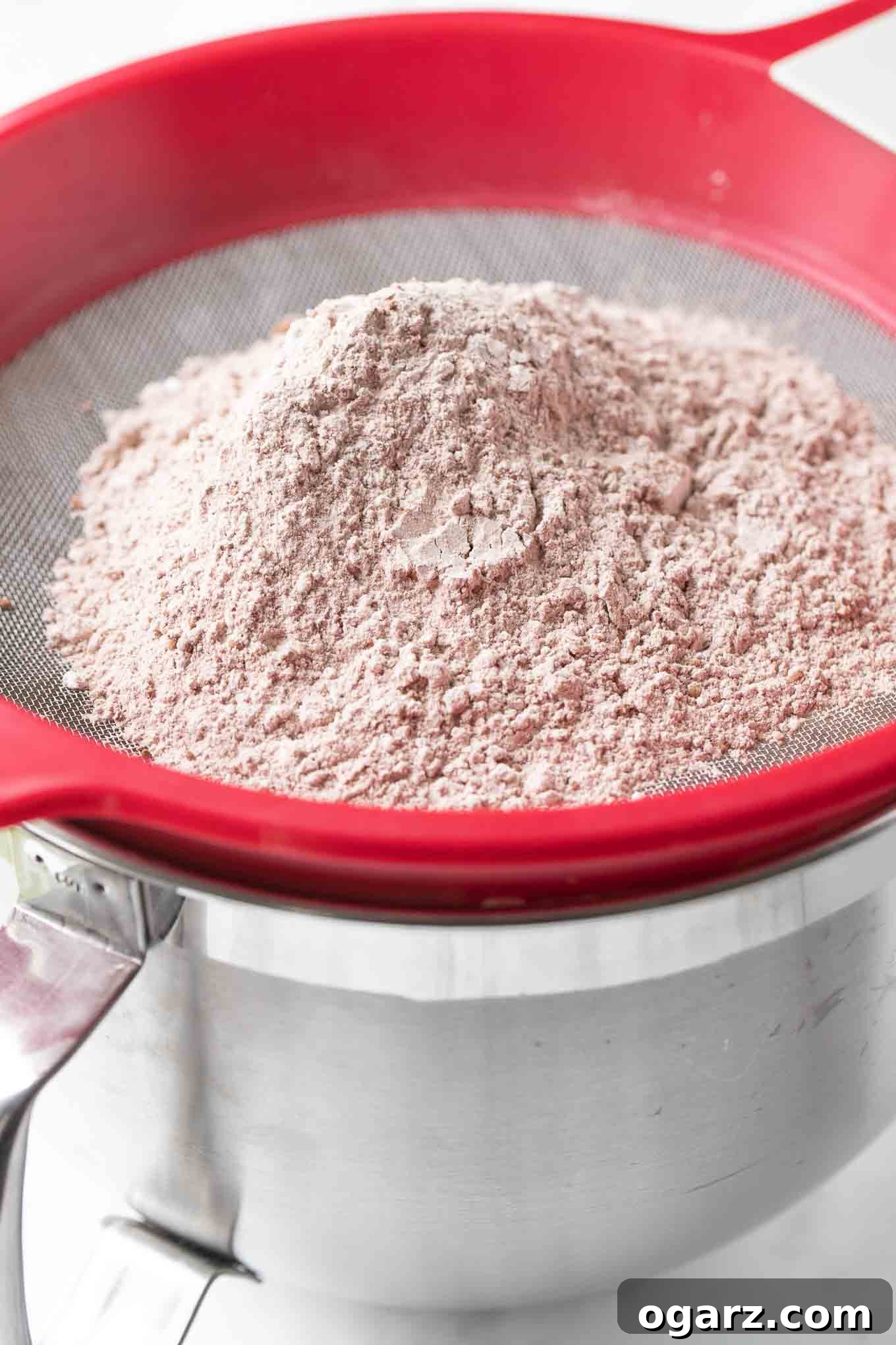 Dark Forest Cherry Delight 6 A flour sifter positioned over a large mixing bowl, containing the delicate egg mixture, ready for the dry ingredients to be gently incorporated.