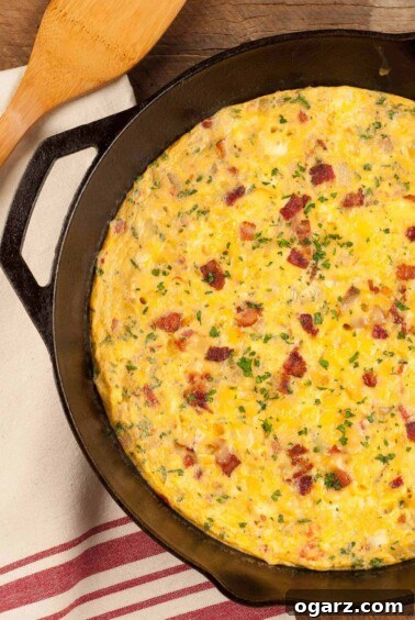 An overhead view of a bacon and cheese frittata in a cast iron pan garnished with extra bacon bits and chopped parsley, ready to serve for brunch.