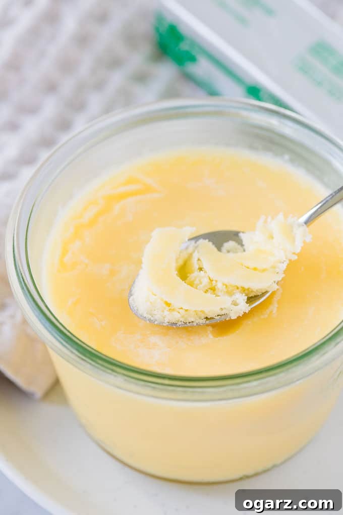 Golden Butter's Pure Essence 2 Clarified Butter in a glass jar, with a spoon.