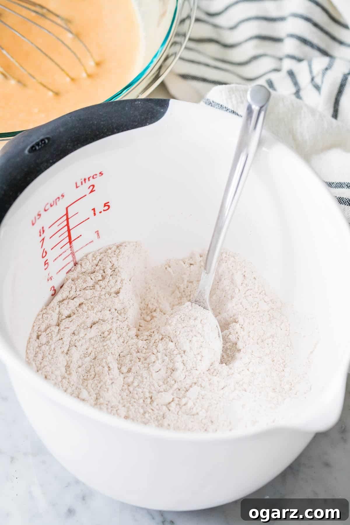 A bowl filled with dry ingredients like flour, sugar, and spices, with a spoon resting inside, ready for mixing.