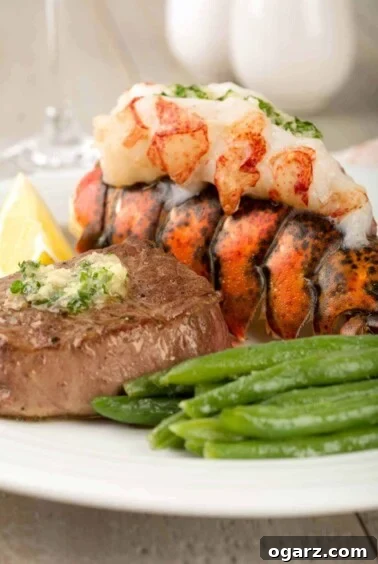A luxurious surf and turf meal featuring a perfectly pan-seared filet mignon topped with fresh parsley butter, paired with a succulent, juicy lobster tail, and a vibrant side of crisp green beans.