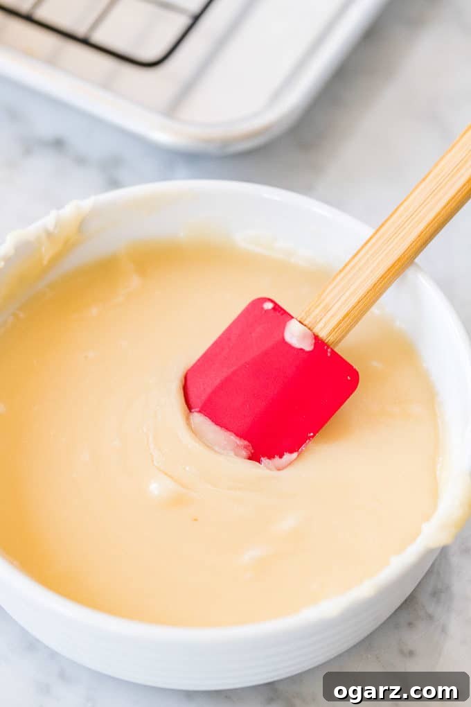 Air-Fried Donut Perfection 7 Air Fryer Donut Glaze in a white bowl with a red spatula, ready for dipping