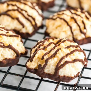 Irresistible Homemade Coconut Macaroons 6 Coconut macaroons with chocolate bottoms and stripes on a black cooling rack.