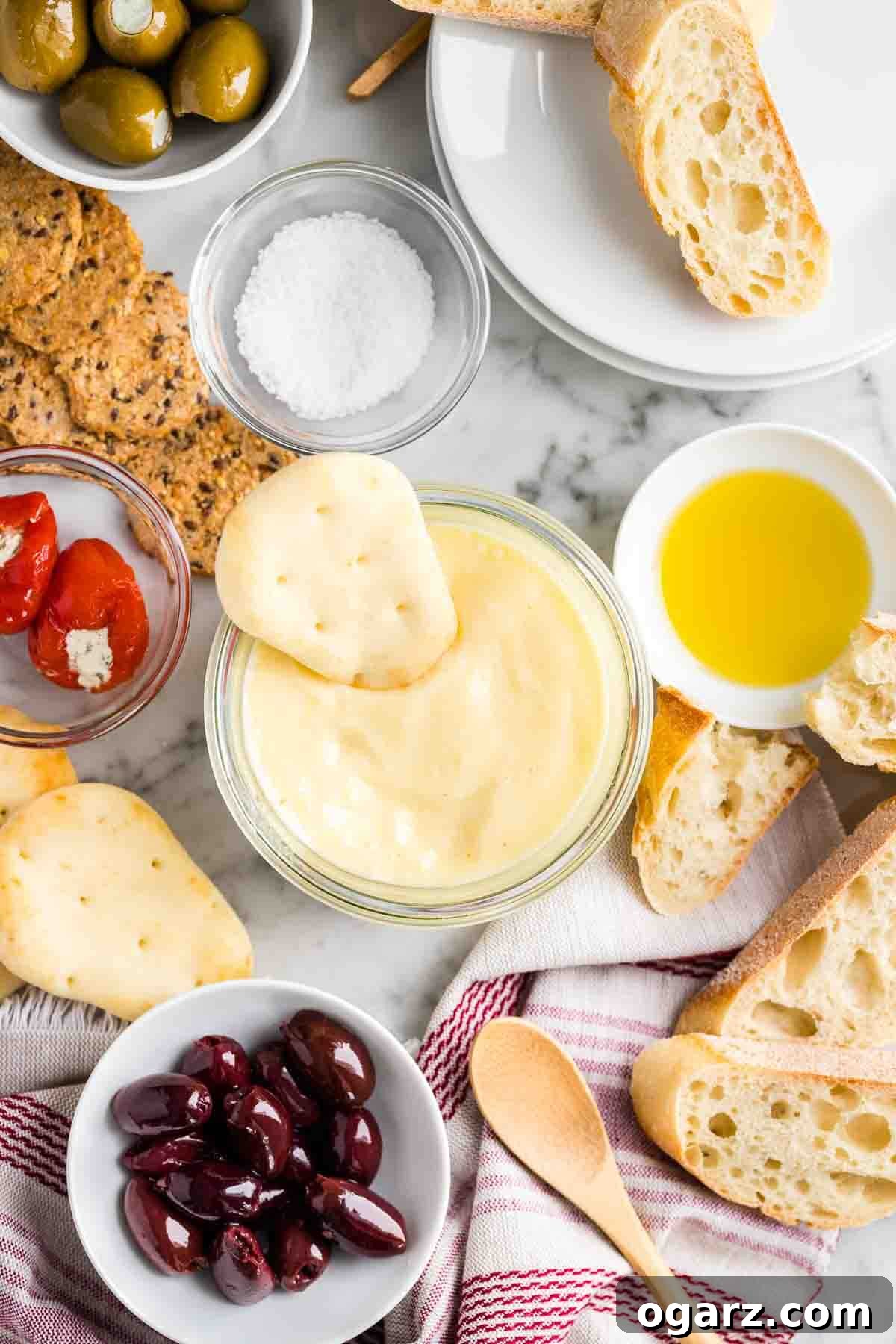 A beautifully presented serving of Aioli sauce accompanied by an assortment of fresh appetizers and crusty bread, ideal for dipping.