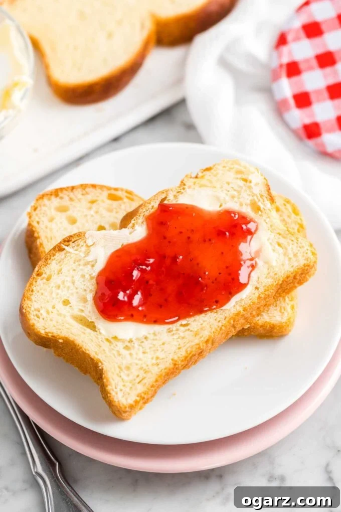 Two slices of brioche bread on a plate, spread with butter and jam, indicating its rich texture and deliciousness.