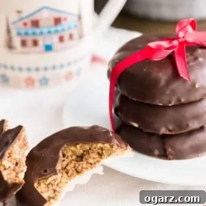 Authentic German Lebkuchen 9 A stack of three chocolate-covered Lebkuchen with a red bow on a white plate next to a Lebkuchen broken in half. There's a cup in the background