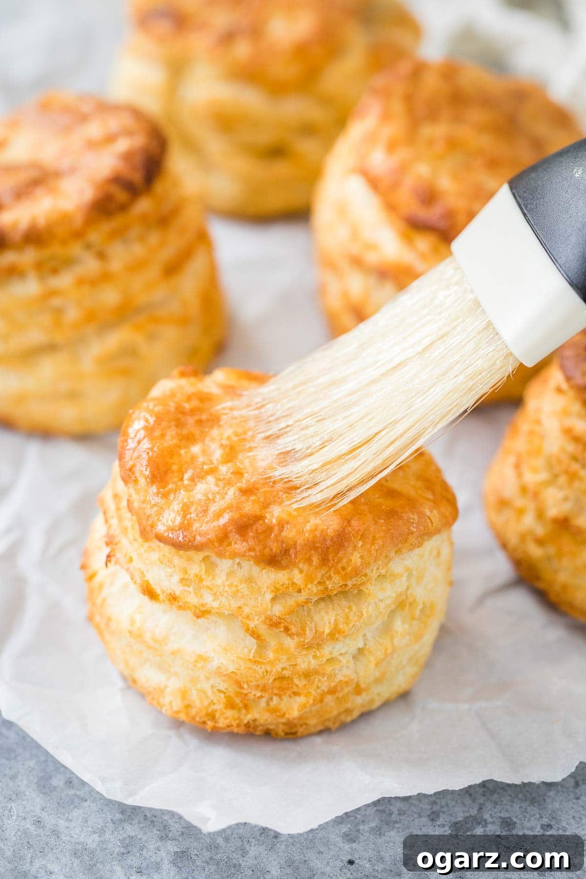 Golden Air Fryer Biscuits 7 Melted butter being brushed onto a warm, freshly baked biscuit, adding a glossy finish.