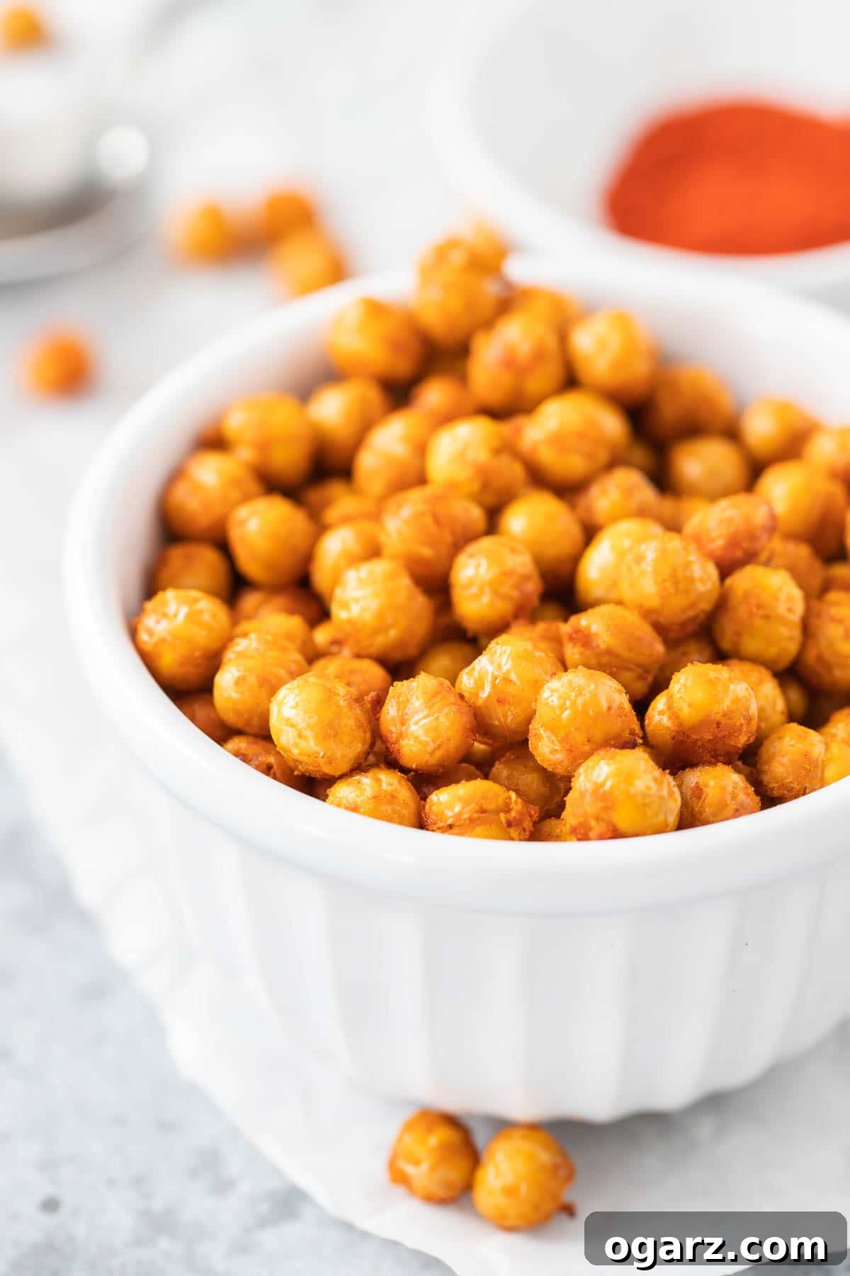 Air fried chickpeas in a white bowl next to a bowl of spices, highlighting their perfect crispness and golden-brown hue.