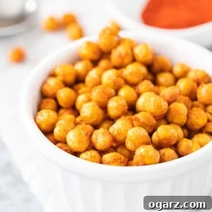 Air fried chickpeas in a white bowl next to a bowl of spices, ready to be enjoyed as a crispy snack.